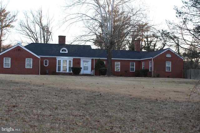 single story home featuring a chimney, a front lawn, and brick siding