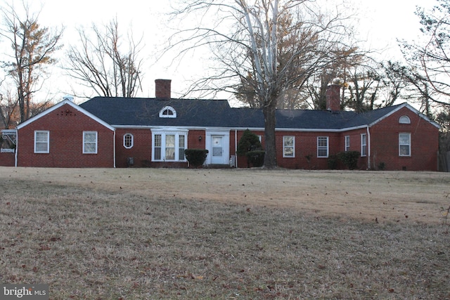 ranch-style home with a front yard, a chimney, and brick siding