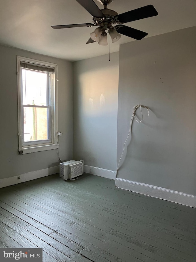 spare room with an AC wall unit, wood finished floors, and baseboards