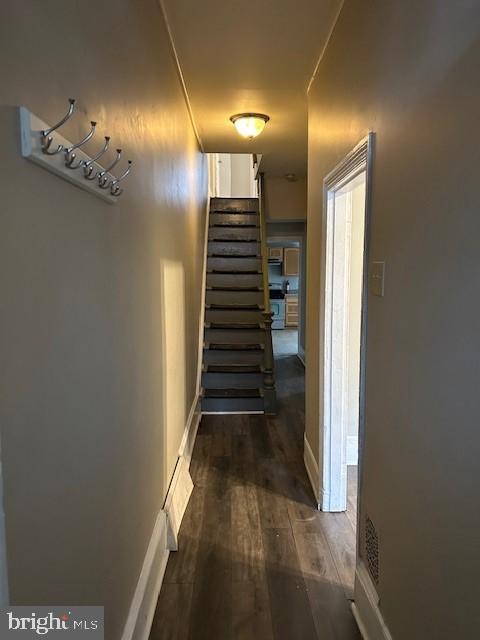 hall featuring stairway, dark wood-style flooring, and baseboards