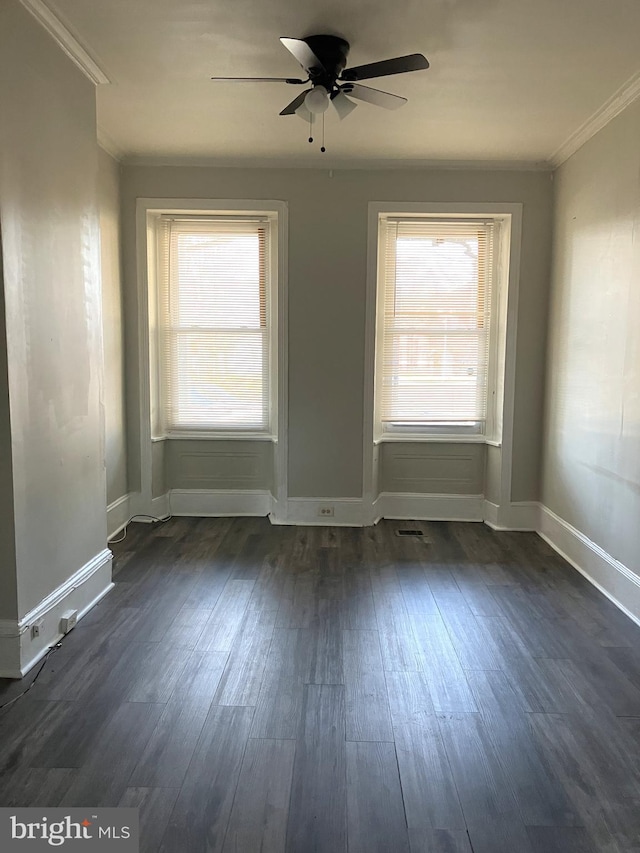 unfurnished room featuring ceiling fan, baseboards, dark wood-type flooring, and crown molding