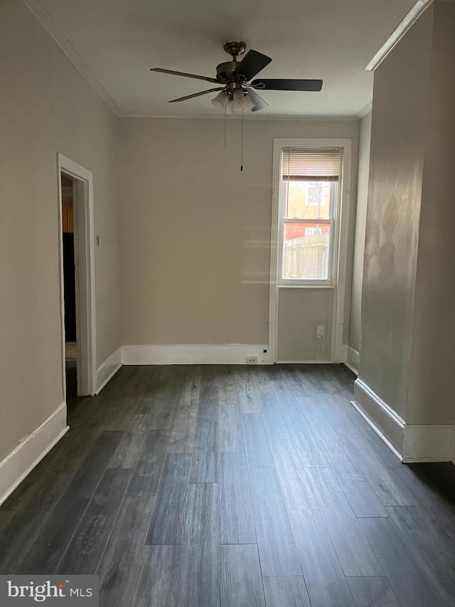 empty room featuring baseboards, ceiling fan, dark wood finished floors, and crown molding