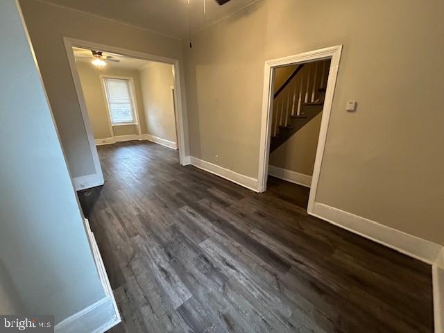 interior space with dark wood-style floors, ceiling fan, baseboards, and stairs