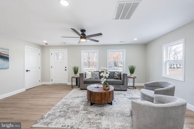 living room featuring plenty of natural light, wood finished floors, visible vents, and baseboards