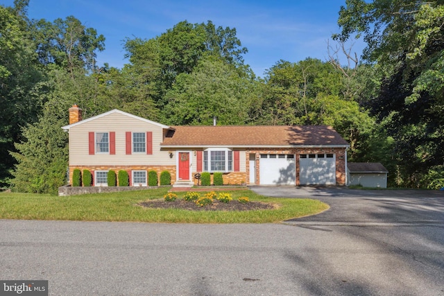 tri-level home with driveway, a garage, a chimney, and brick siding