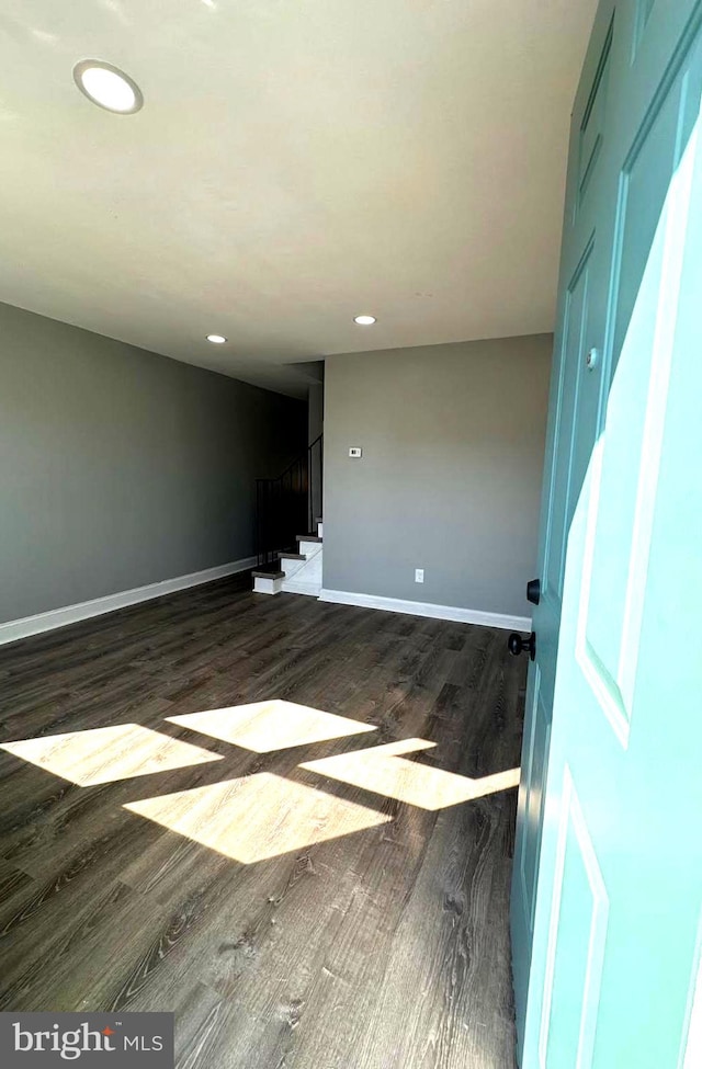 empty room with dark wood-style floors, baseboards, stairway, and recessed lighting