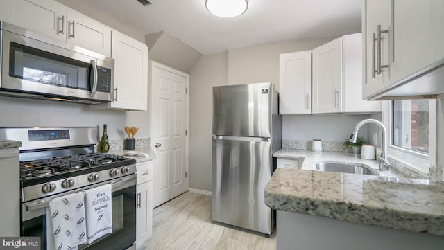 kitchen with white cabinetry, sink, light stone countertops, and appliances with stainless steel finishes