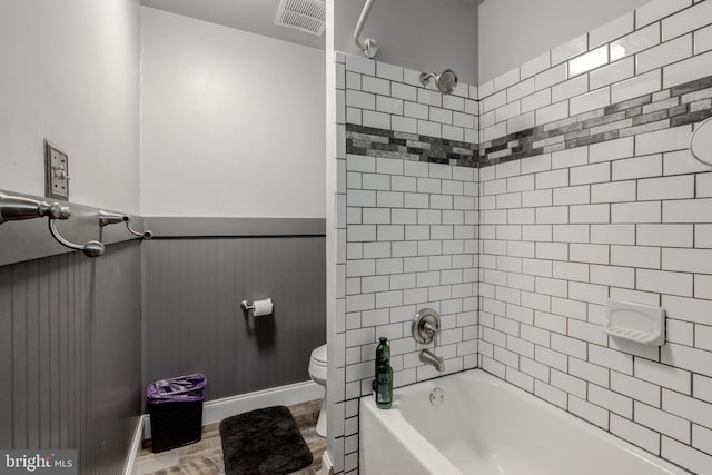 bathroom featuring toilet, tiled shower / bath combo, and hardwood / wood-style floors