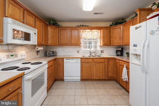 kitchen featuring white appliances, a sink, visible vents, light countertops, and backsplash