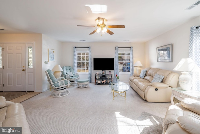 carpeted living area featuring baseboards, visible vents, and a ceiling fan