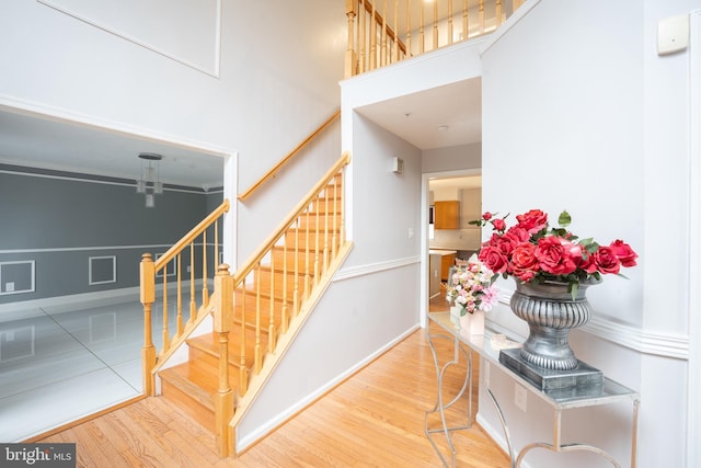 stairs with hardwood / wood-style flooring and a towering ceiling