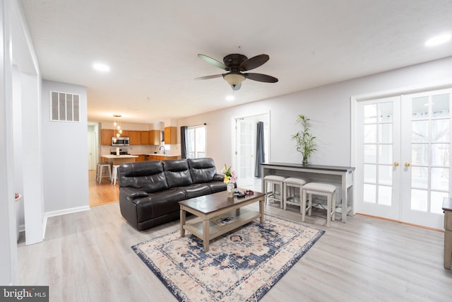 living room with ceiling fan, light wood-type flooring, and french doors