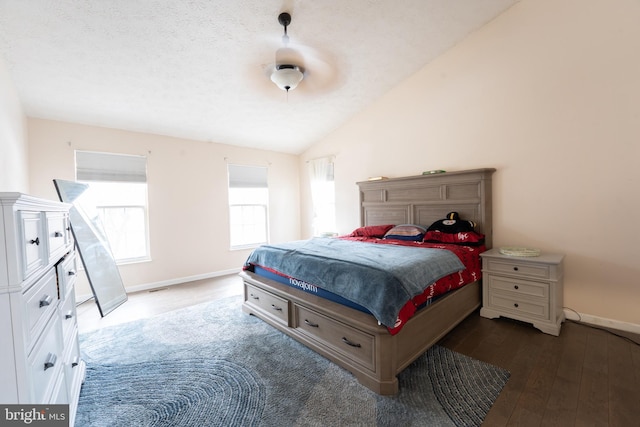 bedroom with vaulted ceiling, dark hardwood / wood-style floors, and a textured ceiling