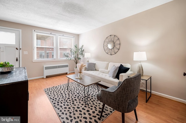 living room featuring radiator heating unit, a textured ceiling, and light wood-type flooring