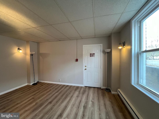 unfurnished room with a drop ceiling, hardwood / wood-style flooring, and baseboard heating