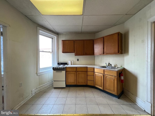 kitchen with a drop ceiling, sink, light tile patterned floors, and white range with electric cooktop