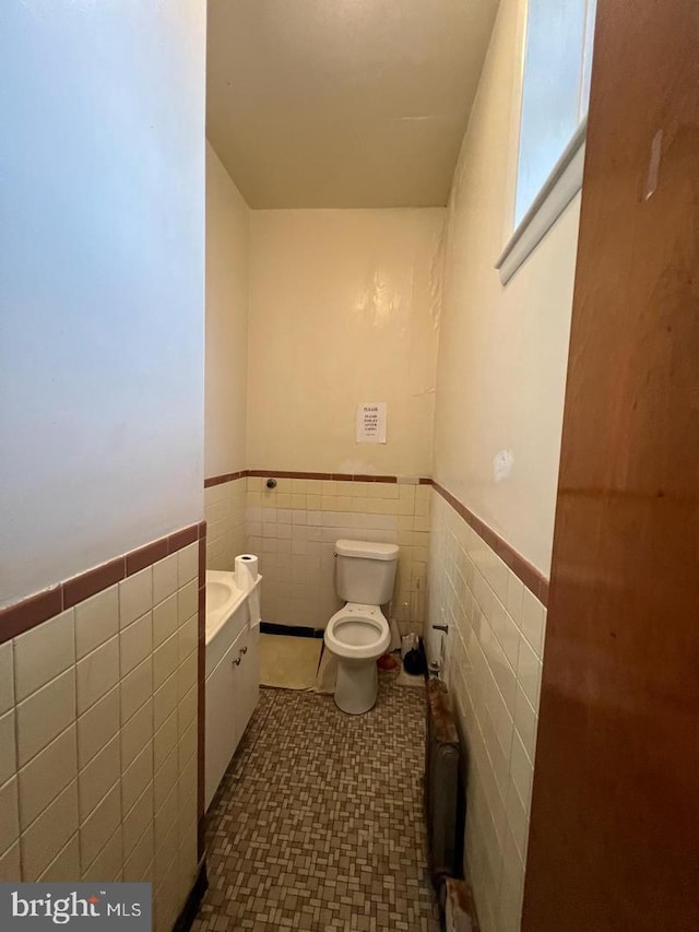 bathroom with vanity, radiator, tile walls, and toilet