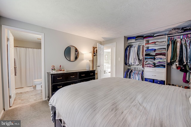 bedroom with light carpet, a closet, connected bathroom, and a textured ceiling