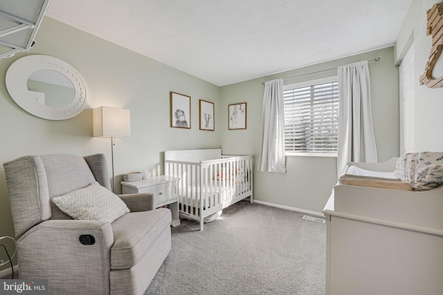 carpeted bedroom featuring a nursery area