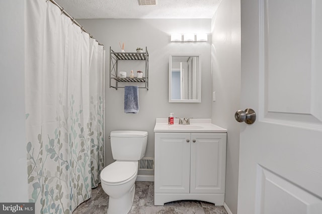 bathroom with toilet, vanity, and a textured ceiling