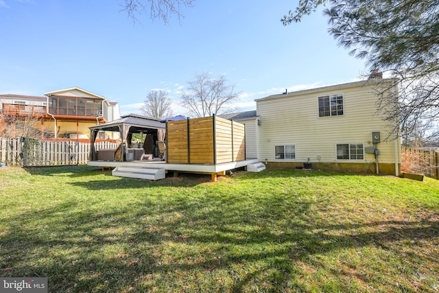 rear view of property featuring a lawn, a deck, and a gazebo