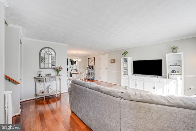 living room featuring a textured ceiling, crown molding, dark hardwood / wood-style floors, and an inviting chandelier