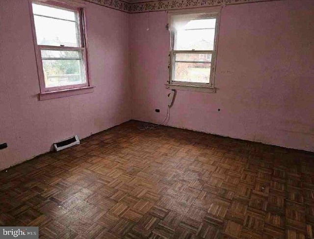 empty room featuring dark parquet floors and a wealth of natural light