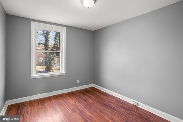 empty room with dark wood-style floors and baseboards