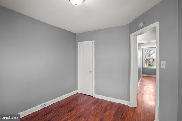 unfurnished bedroom featuring dark wood-style floors, a closet, and baseboards