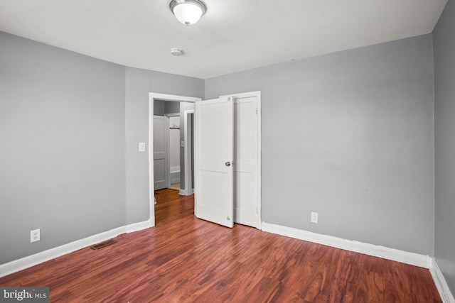 unfurnished bedroom featuring wood finished floors, visible vents, and baseboards