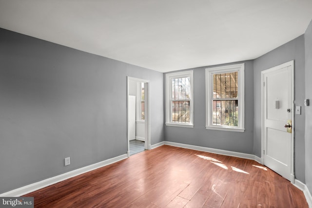 spare room with baseboards and wood finished floors