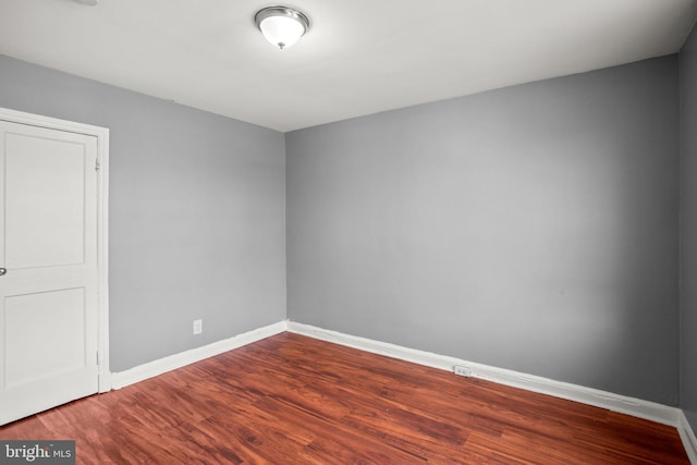 spare room with baseboards and wood finished floors