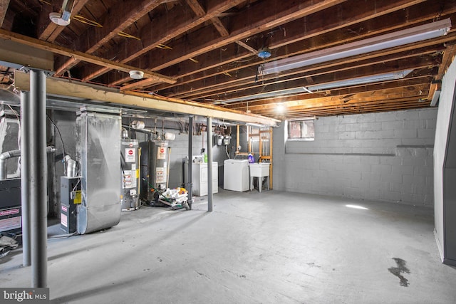 below grade area featuring gas water heater, a sink, and separate washer and dryer