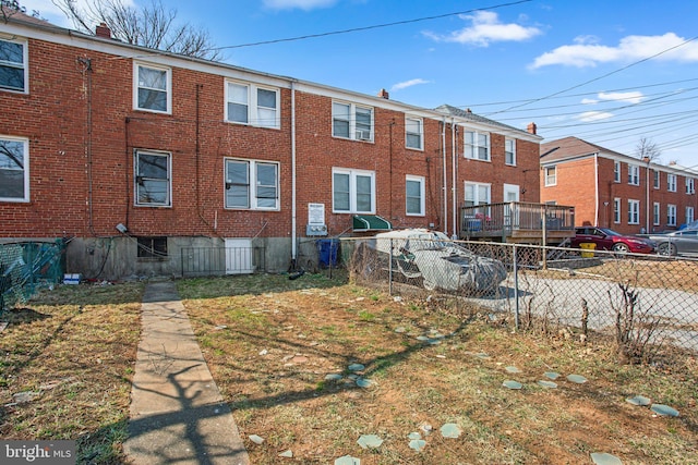 rear view of property with brick siding and fence