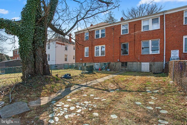 back of property with brick siding, a chimney, and fence