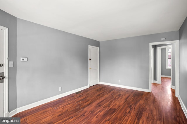 unfurnished room featuring baseboards and dark wood-style flooring