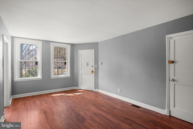 spare room with baseboards, visible vents, and wood finished floors