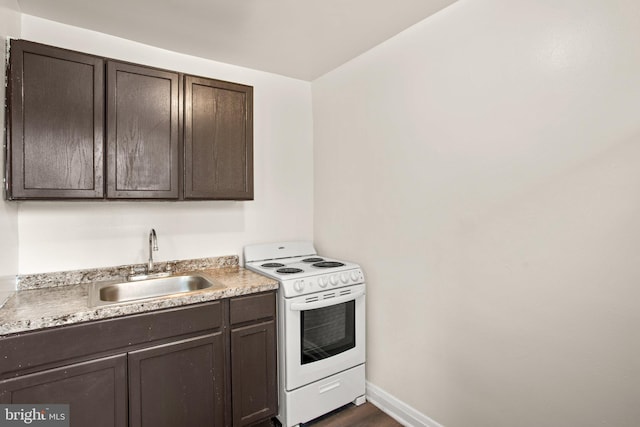 kitchen with white range with electric stovetop, baseboards, light countertops, dark brown cabinets, and a sink