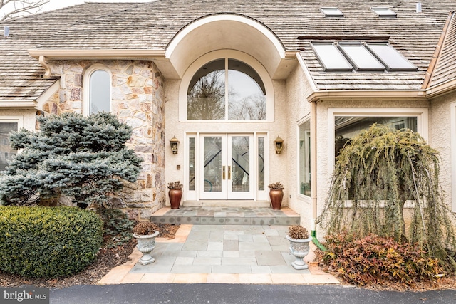 property entrance featuring stone siding, french doors, and stucco siding