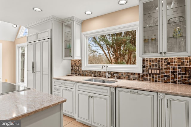 kitchen featuring paneled fridge, glass insert cabinets, white cabinets, and a sink