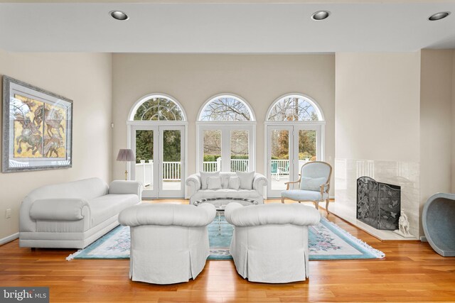 living area with baseboards, a fireplace, light wood-style flooring, and recessed lighting