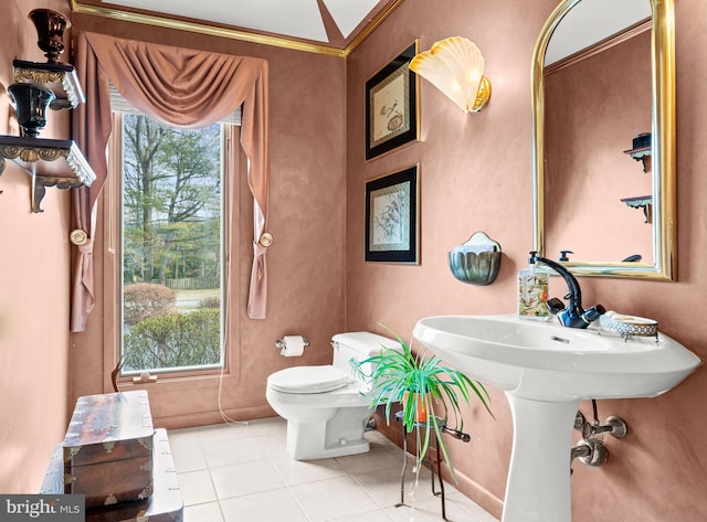 half bathroom featuring toilet, plenty of natural light, crown molding, and tile patterned floors