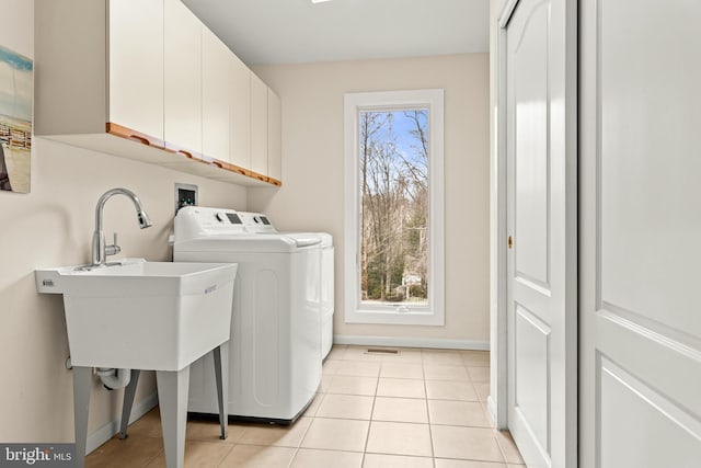 clothes washing area featuring light tile patterned floors, a sink, visible vents, washer and dryer, and cabinet space