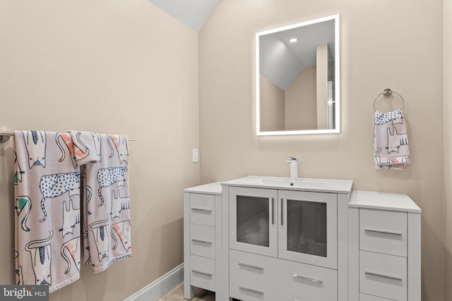 bathroom featuring vaulted ceiling, vanity, and baseboards