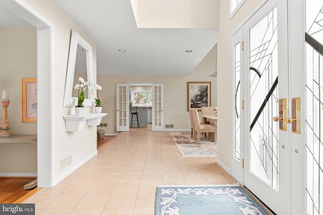 foyer entrance with french doors, light tile patterned flooring, visible vents, and baseboards