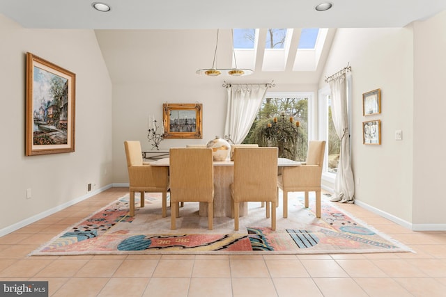 dining area featuring vaulted ceiling with skylight, baseboards, and light tile patterned flooring