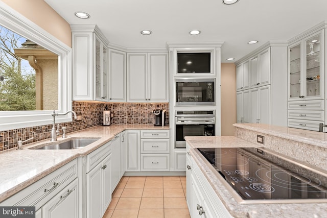 kitchen with glass insert cabinets, white cabinets, a sink, and black appliances