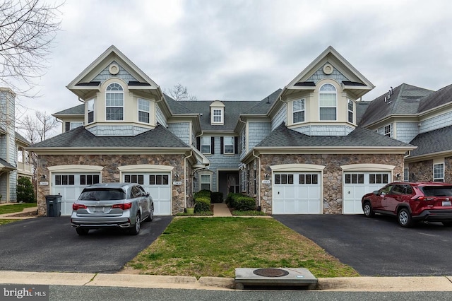 view of front of property featuring an attached garage, a shingled roof, driveway, stone siding, and a front yard