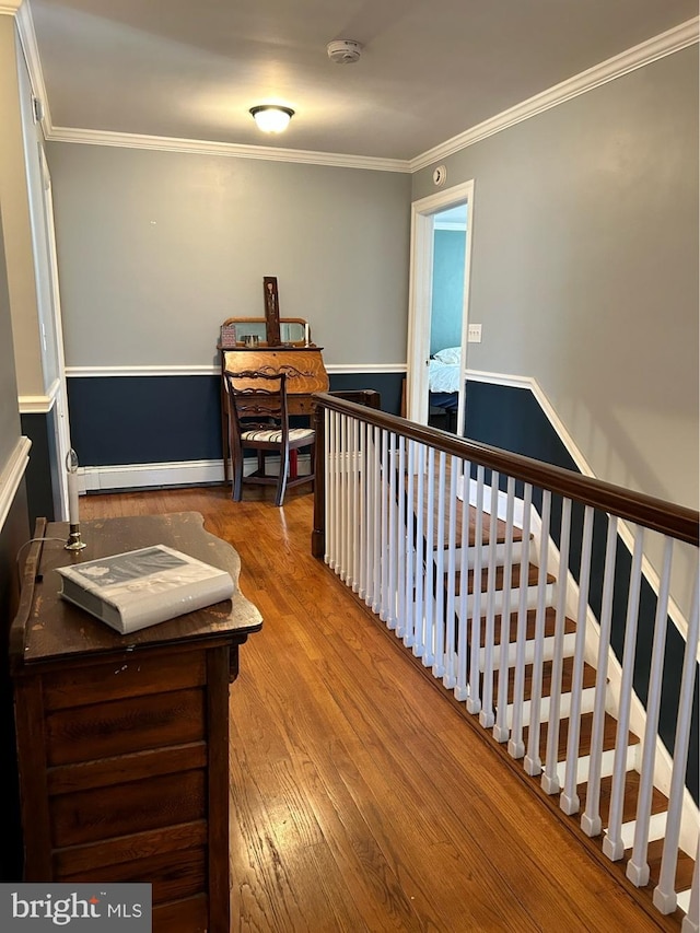 corridor featuring ornamental molding, wood-type flooring, and a baseboard heating unit