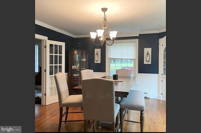 dining space with dark wood-type flooring, ornamental molding, and a chandelier